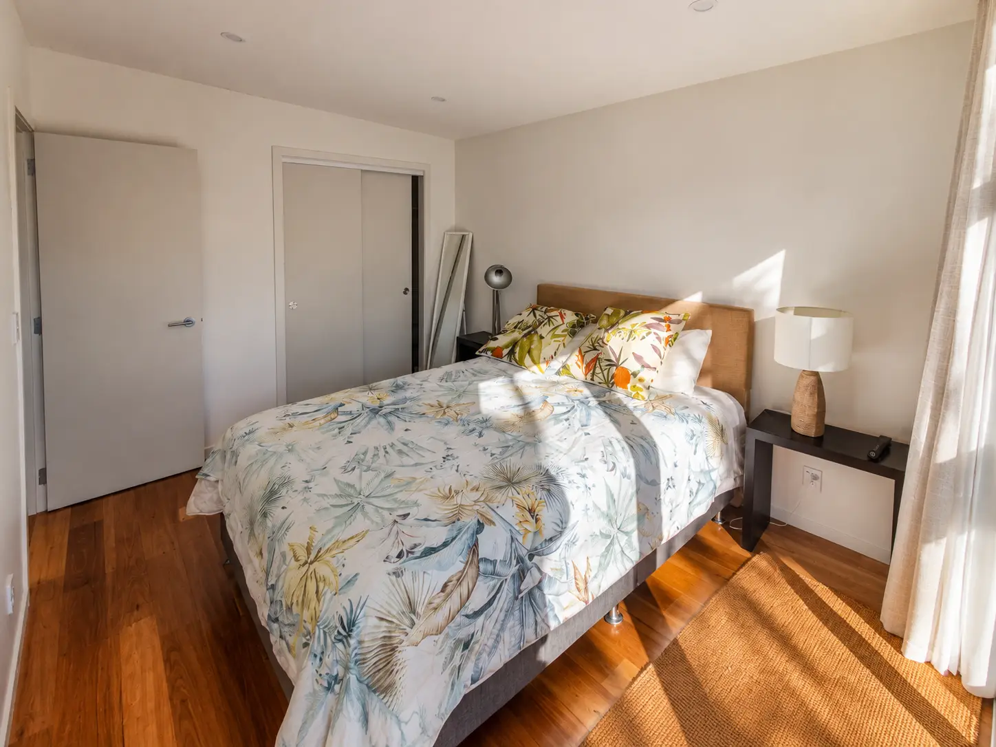 The bedroom — the bed under the window with the wardrobe run and the doorway through to the rest of the accommodation.