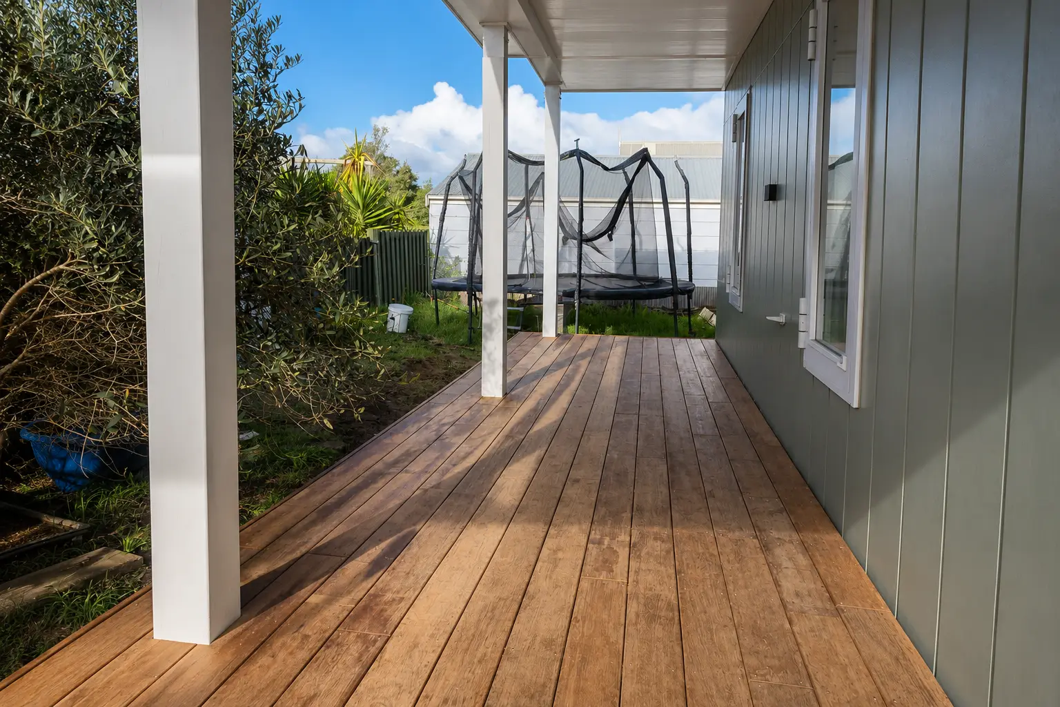 The finished deck looking along its length under the veranda roof, the boards running away between the house wall and the garden.
