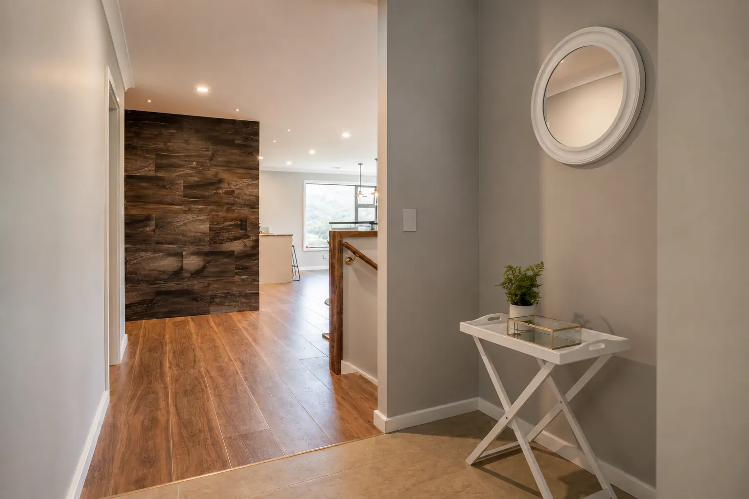 The entry — tile meeting timber at a flush junction, and the plank-tile feature wall at the end of the hall where the kitchen begins.