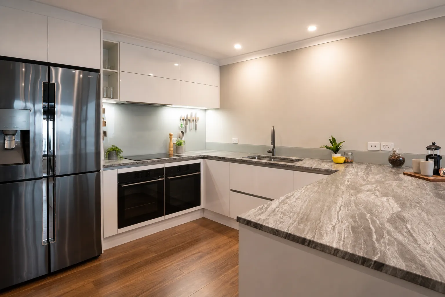 The main kitchen — stone benchtop and peninsula, with the under-cabinet lighting on over the working length of the bench.