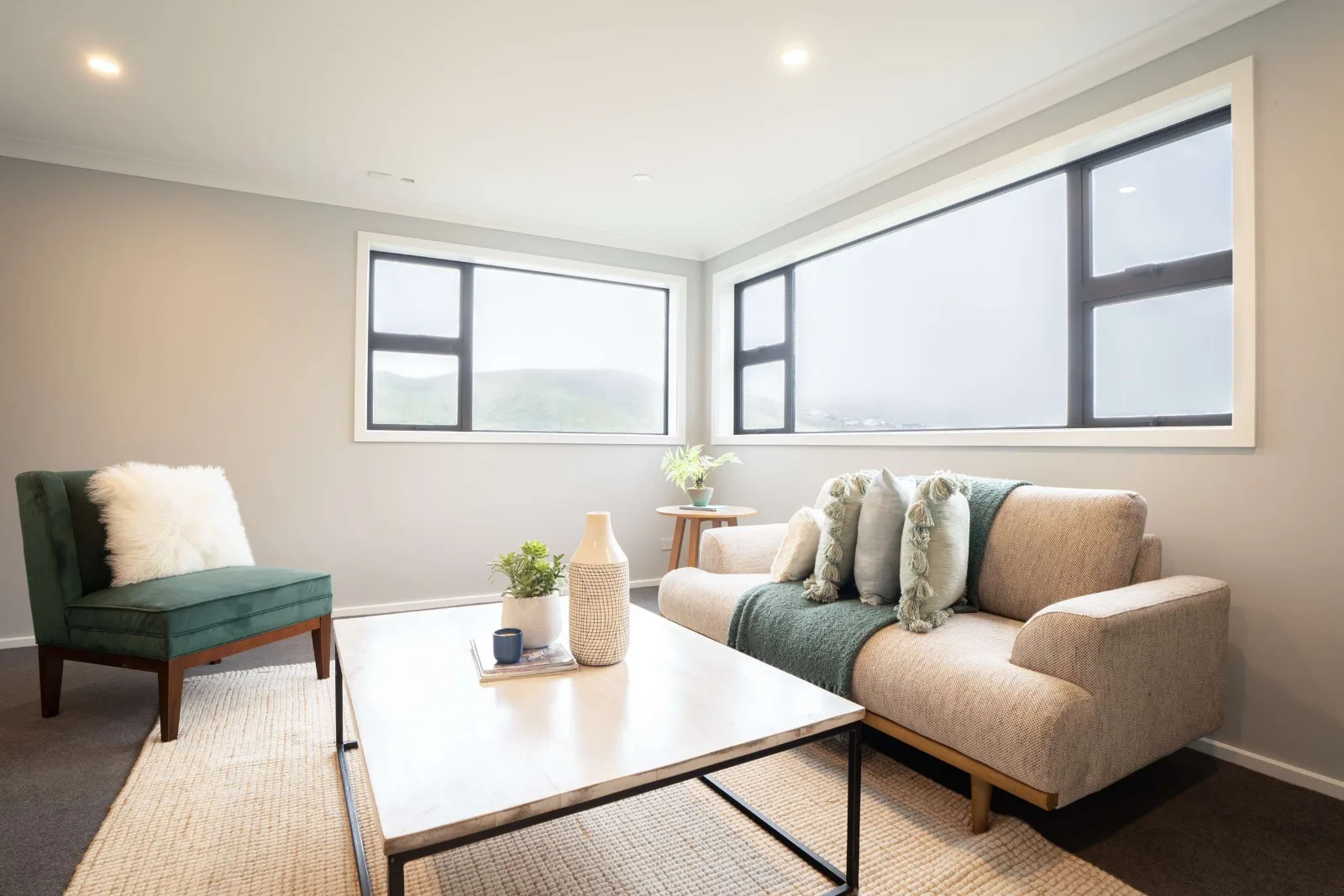 The same room from the other end, its two windows meeting over the hills and the sofa set beneath them.