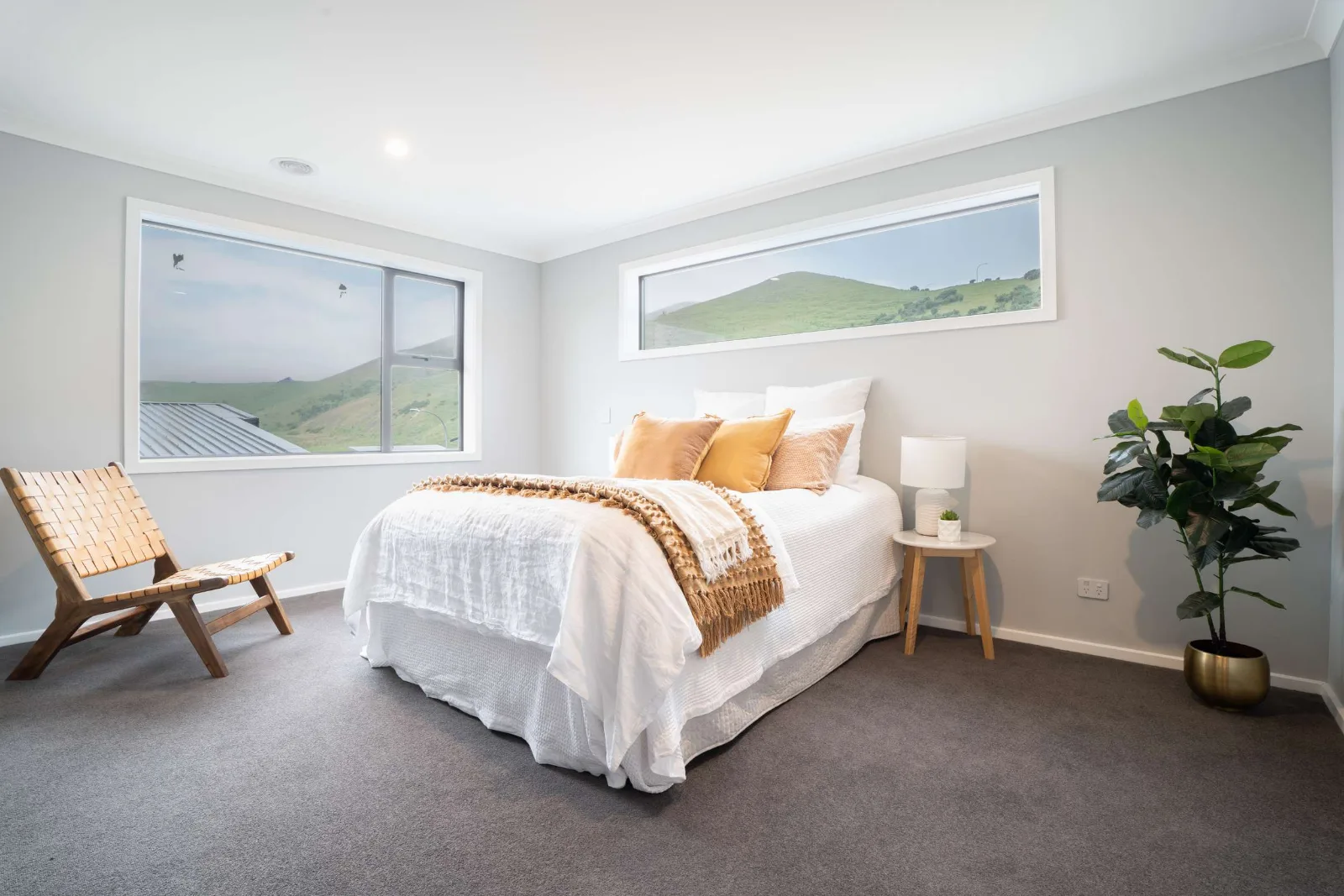 A second bedroom — a high clerestory window above the bedhead and a long low window to the hills, carrying daylight without looking into the neighbours.